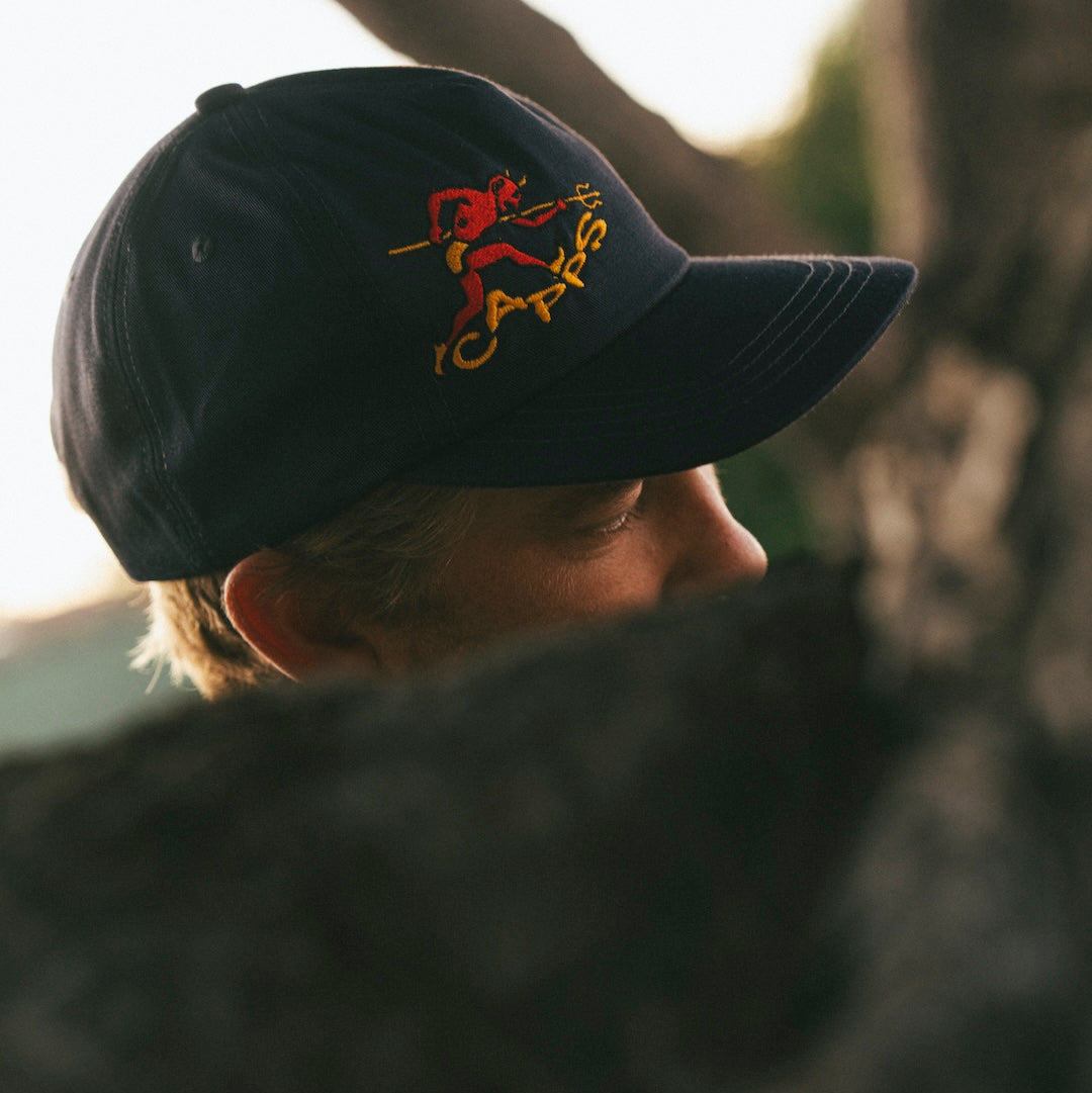Person wearing a black cap with a red and yellow logo, looking away from the camera.